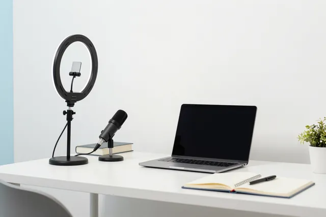 A home desk set up to record a lesson with a ring light, a microphone and a laptop